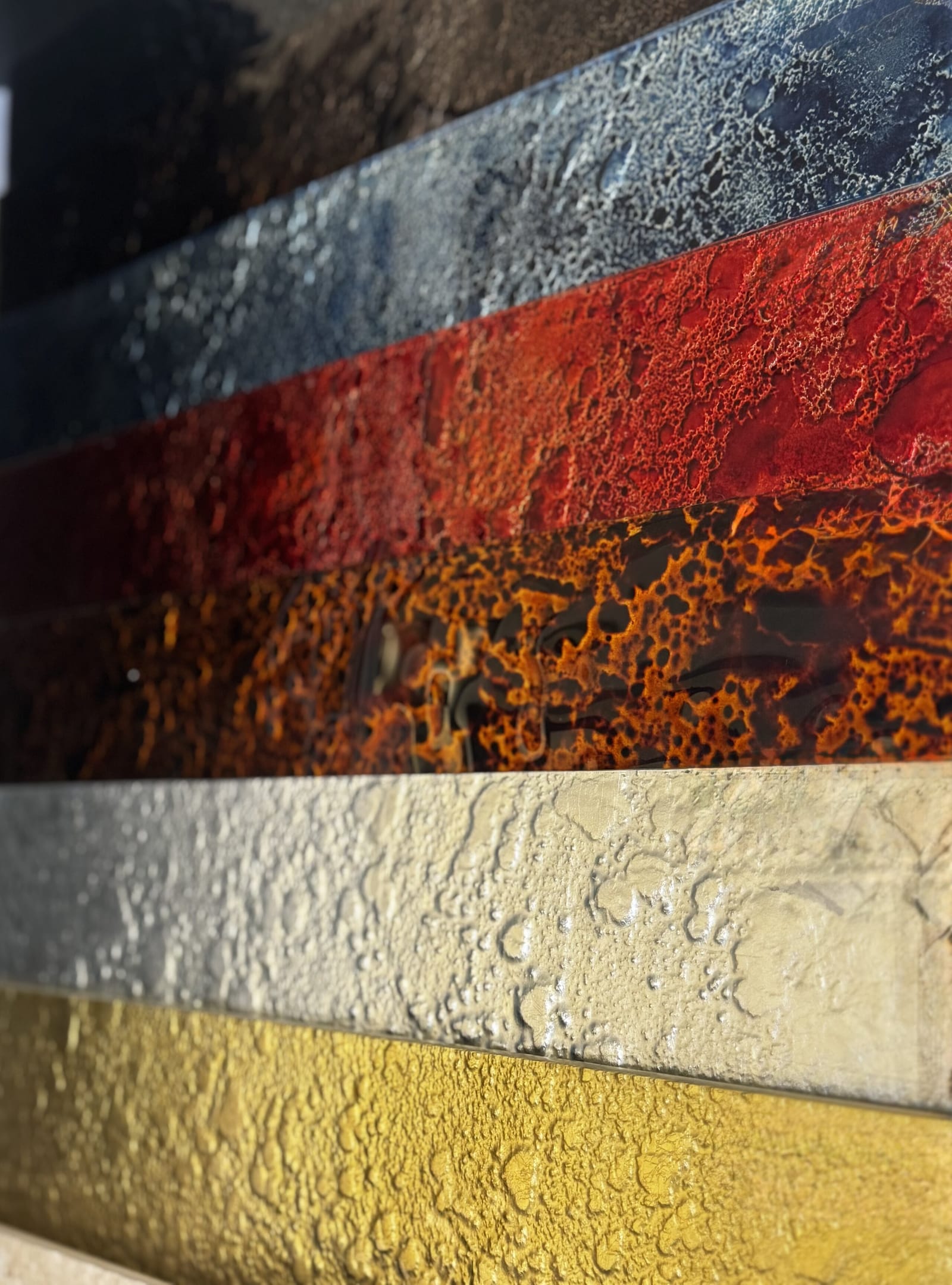Wandpaneele in Rost-Rot und Gold mit reliefartiger Struktur, darunter helle Steinfliese.