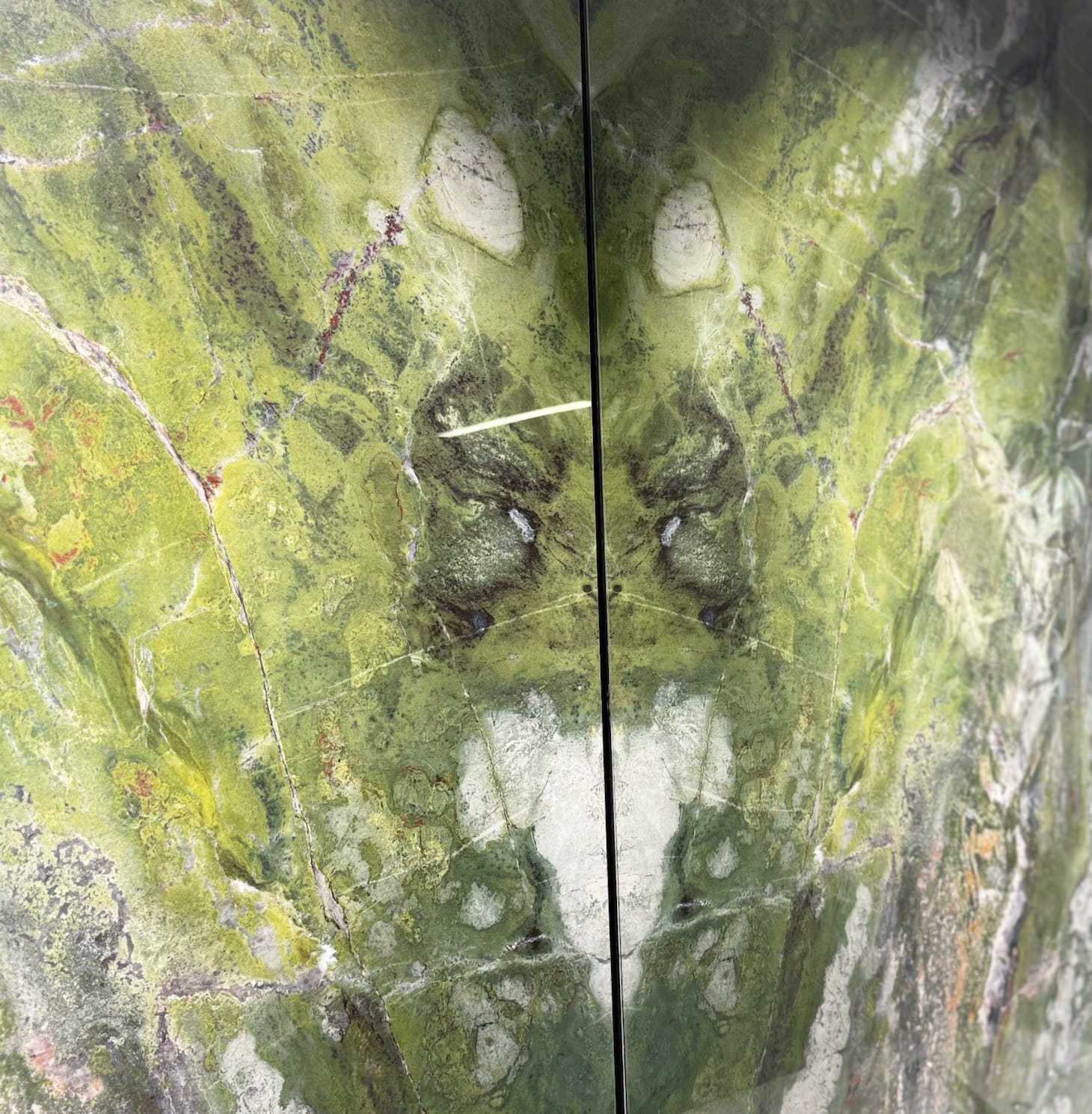 Zwei gespiegelte Natursteinplatten mit grüner Aderung, im Buchmatch nebeneinander montiert.