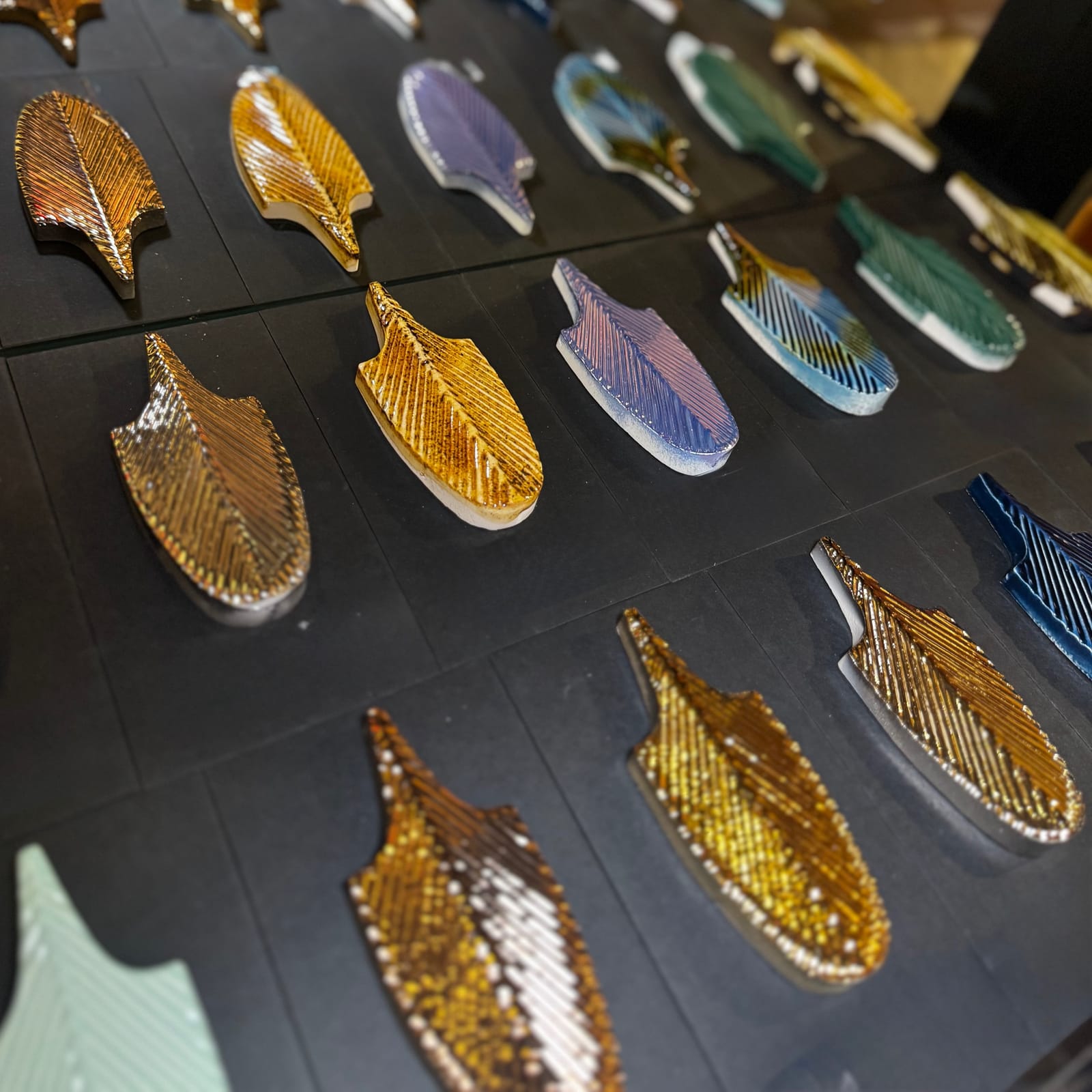 Zierfische aus buntem Glasmosaik auf dunkler Wandfläche